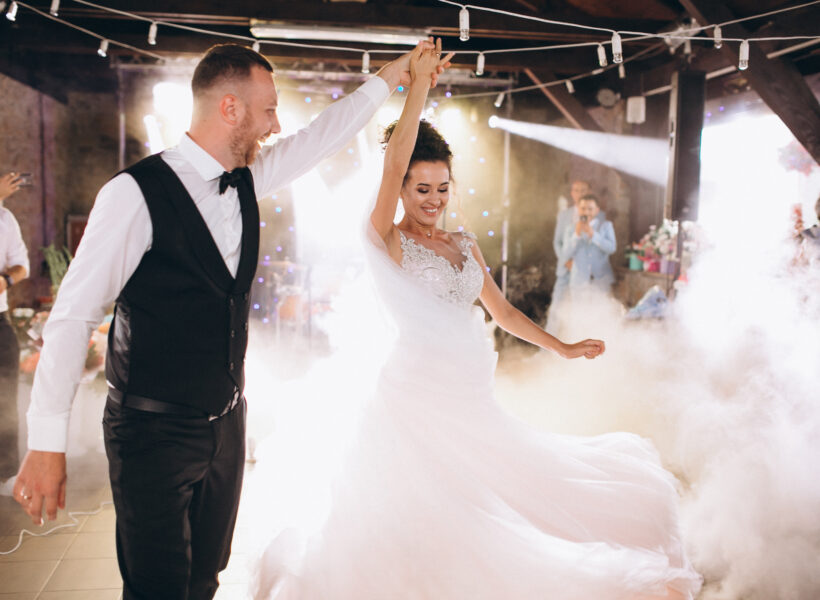 Couple de mariés dansant l'ouverture de bal sur un tapis de fumée lourde avec éclairage asservi par Art Scène Animation en Normandie.